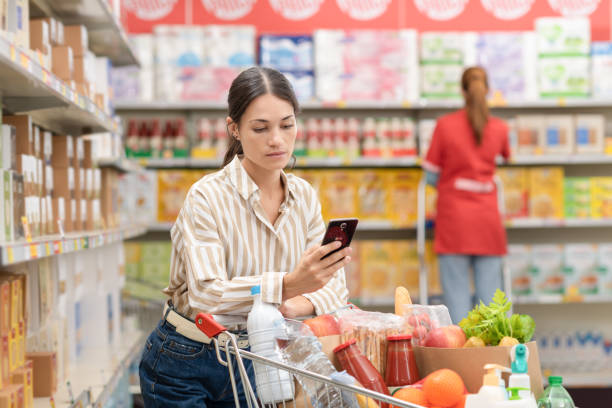 istock Woman using her smartphone at the grocery store 2054979982