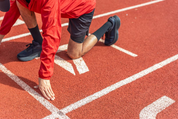 istock Close up runner man using starting block to start his run on running track background, outdoor workout concept, drink clear mineral water after jogging. Generation z lifestyle. 2054983160