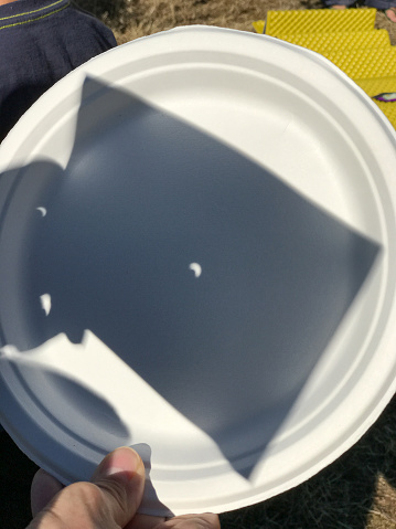 Solar Eclipse. The sun shadow reflected on a plastic dish.