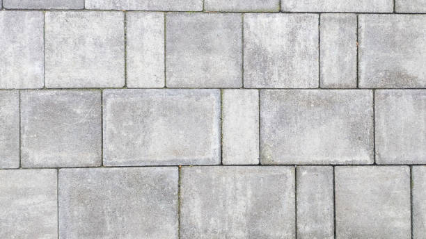 istock Close up of pebbly gray cement bricks paving a textured road. 2055022433