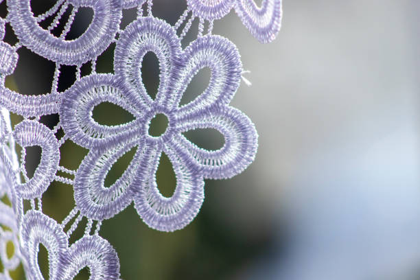 Detail of white lace curtain with flower pattern, in a home interior setting.