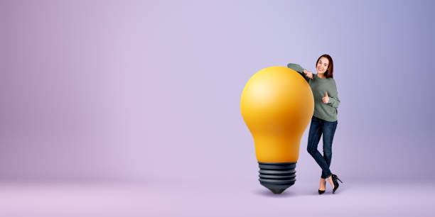 istock Woman showing thumb up standing near big light bulb on empty background 2055022454