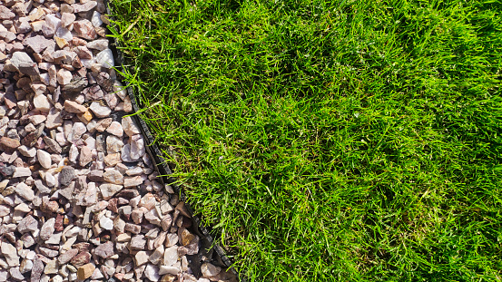Lush green lawn with a border of garden pebbles