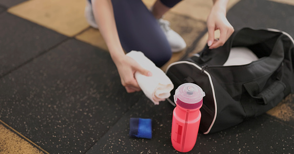 closeup view on sport equipment - asian female take out  water bottle and other tools ready for doing exercise at gym
