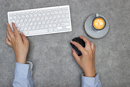 top view of desktop, close up of business female hands typing on grunge gray table