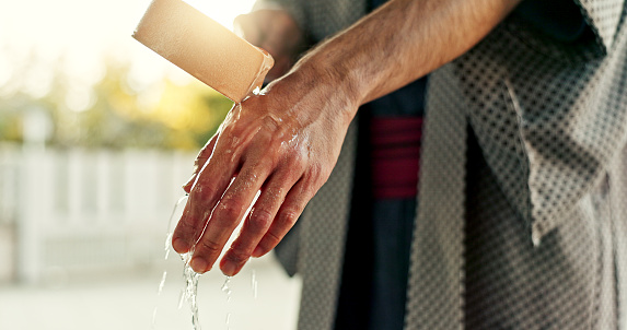 Person and washing hands at fountain with container for cleaning, faith and worship. Religion, mindfulness and purification ritual to stop evil, bacteria and peace in Tokyo