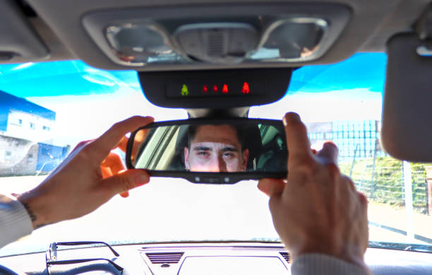 istock Caucasian man adjusting car rearview mirror seeing himself reflected 2055108291