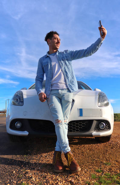 istock Curly haired Caucasian man leaning on his car smiling taking a selfie 2055125980