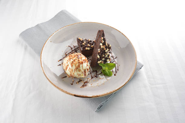 istock walnut chocolate brownie with vanilla ice cream and peanut, chocolate sauce, mint leaf dessert in round plate on white table western asian cafe halal dessert restaurant pastry menu 2055133325