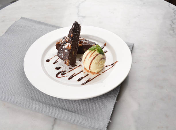 istock walnut chocolate brownie with vanilla ice cream and peanut, chocolate sauce, mint leaf dessert in round plate on white table western asian cafe halal dessert restaurant pastry menu 2055133878