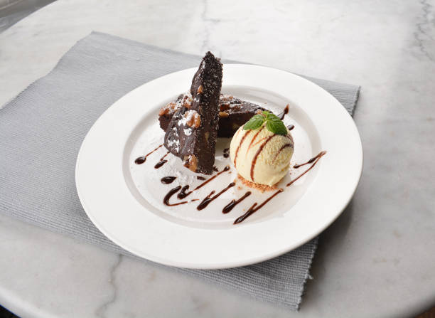 istock walnut chocolate brownie with vanilla ice cream and peanut, chocolate sauce, mint leaf dessert in round plate on white table western asian cafe halal dessert restaurant pastry menu 2055134383