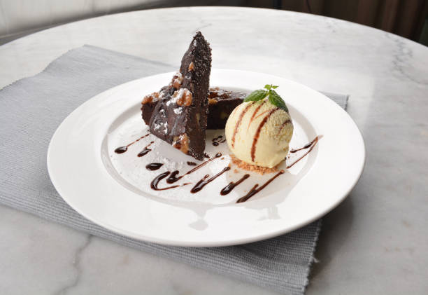 istock walnut chocolate brownie with vanilla ice cream and peanut, chocolate sauce, mint leaf dessert in round plate on white table western asian cafe halal dessert restaurant pastry menu 2055134405