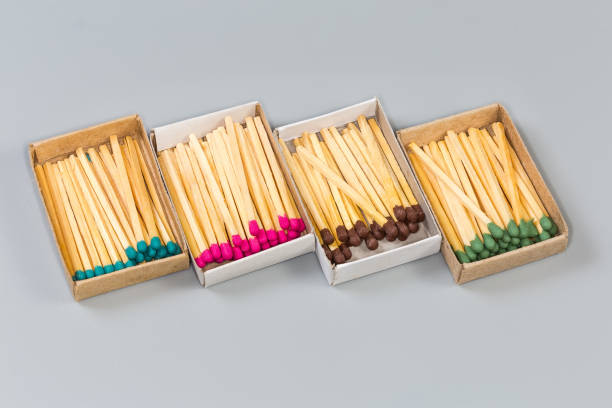 Several open usual cardboard matchboxes with wooden household safety matches with heads of different colors on a gray surface