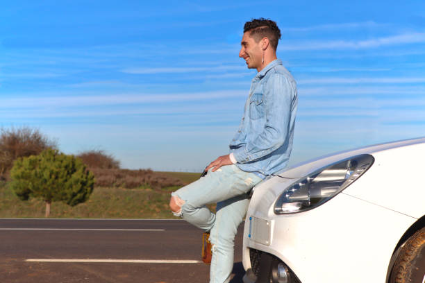 istock Curly Haired Caucasian man leaning on car trunk smiling 2055190083