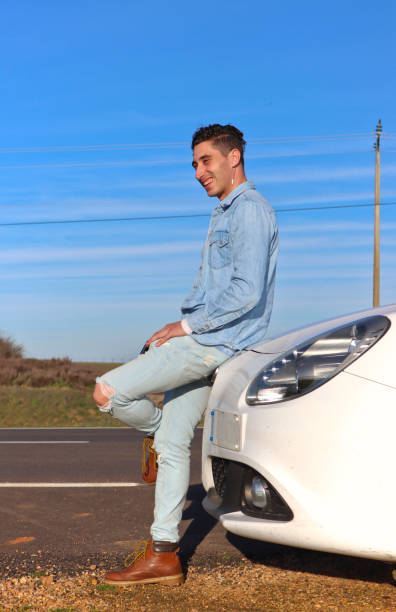 istock Curly Haired Caucasian man leaning on car trunk smiling 2055190612