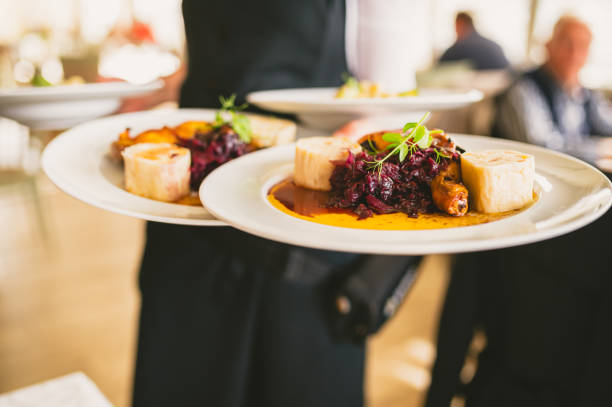 Waiter carrying multiple plates with red cabbage and chicken dish