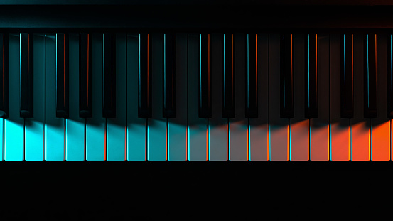 Keys of a keyboard instrument (piano, grand piano, synthesizer) with color blue and red backlight. Atmospheric music, concert, advertising of music training courses or relaxing easy listening cover.