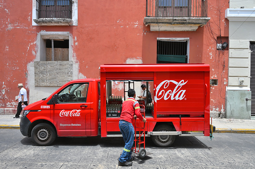 Merida, Mexico - July 21, 2023: Unidentified people at Coca-Cola truck at street of Merida city old town, Yucatan, Mexico
