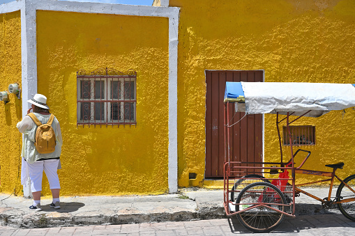 Izamal, Mexico - July 19, 2023: Unidentified people at colorful colonial style buildings at street of Izmal city old town, Mexico