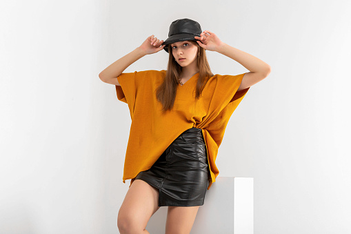 Beautiful business woman. She wears blouse, leather mini skirt and hat.