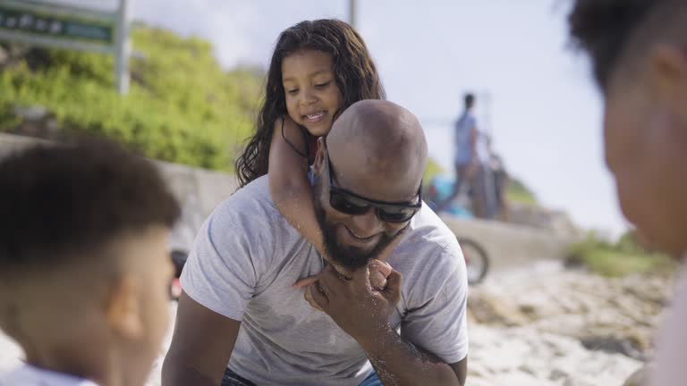 Gay couple playing with their two children on beach