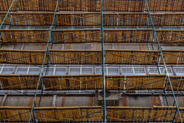 Restoration of a damaged reinforced concrete structure - weathered reinforced concrete structure with damaged and rusty metallic reinforcement  and metal scaffolding on a construction site