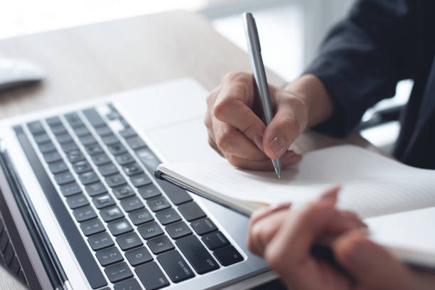 istock Business woman hands with a pen writing on notebook planner and browsing the internet on laptop computer. Business woman planning, online working on laptop computer, project planning 2055314933