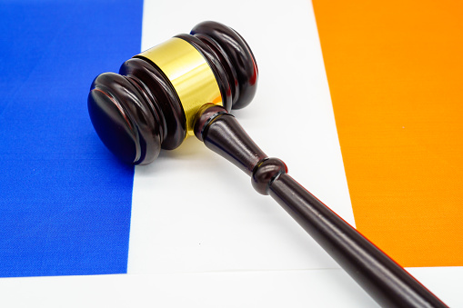 A judges gavel rests against the vibrant backdrop of the French flag, symbolizing legal authority in France