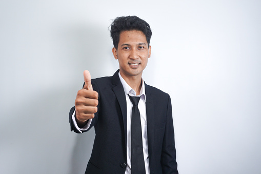 Good luck, nice work. Close-up portrait of satisfied, handsome Asian man show thumb-up in like, approval or recommend sign, give his permission, something in legit, white background