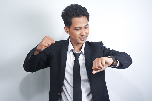 handsome asian man in suit happy and surprised looking at his watch.