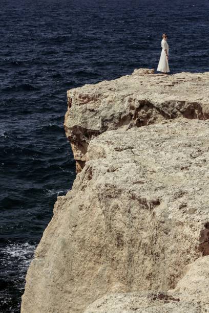 mulher em um vestido branco na beira de um penhasco à beira-mar - hiking coastline waters edge sunny - fotografias e filmes do acervo