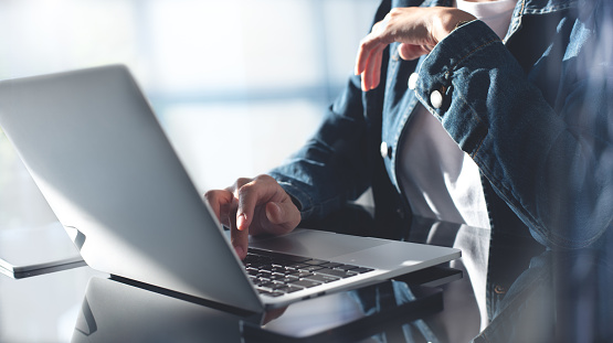 Closeup, business woman hands working and typing on laptop keyboard on glass table. Woman freelancer online working on laptop from home office, remotely work, distant job, social networking