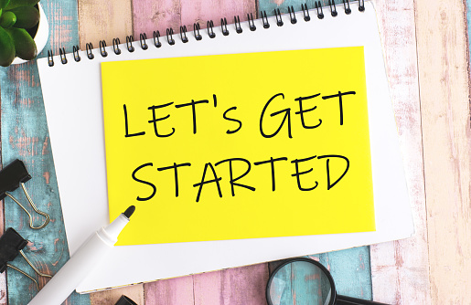 text 'LET'S GET STARTED' on a sheet against a multicolored background suggests the beginning or initiation of a task, project, or journey. It implies motivation and readiness to take action.