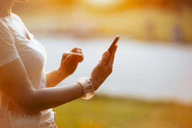 Summer time. Closeup on woman in white shirt using smartphone app.