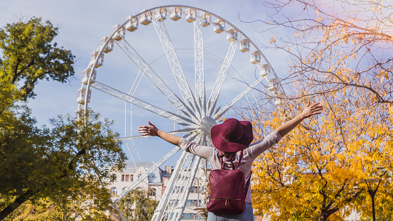 A happy young woman stop near the Budapest Eye big Ferris wheel in Budapest, Hungary in sunny day