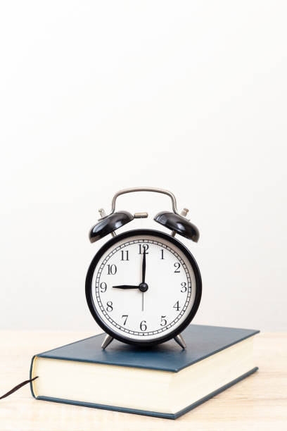 istock A thick book and a clock on the desk. 2055479815