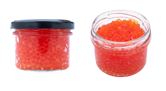 Red caviar in the glass jar isolated on a white background. Trout or salmon caviar close up. Macro shot.