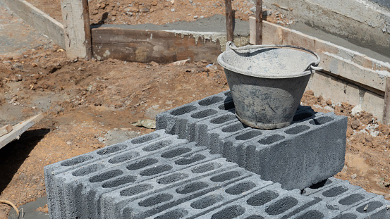Construction background. Bricks and blocks are arranged in neat piles on the ground. And there was a bucket of cement placed on top. Construction wall background.