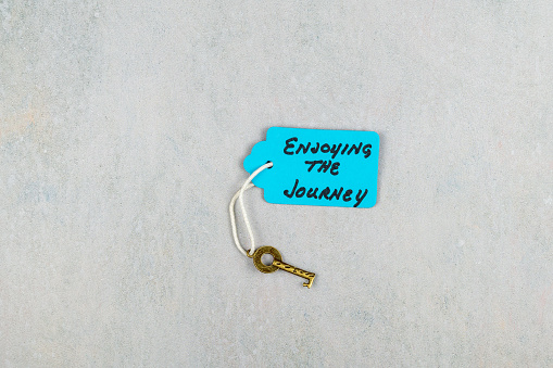 Key to Enjoying the Journey Concept with key and tag on marble surface