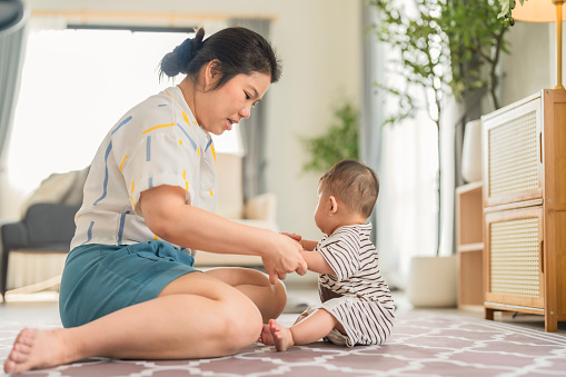 asian family happy activity Babies are learning to crawl mother support nearby Asian mother and little baby to crawl on the floor in the living room Mother and baby sit together in living room home interior background