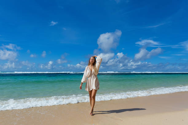 istock Young woman walks barefoot on the beach 2055566211