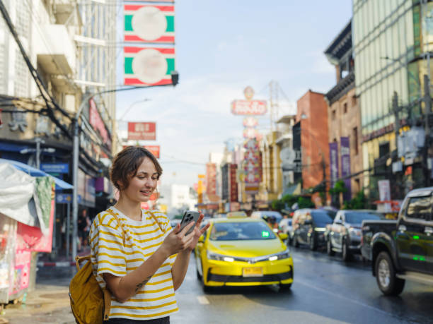 istock Woman using smartphone while walking in Chinatown in Bangkok 2055569844