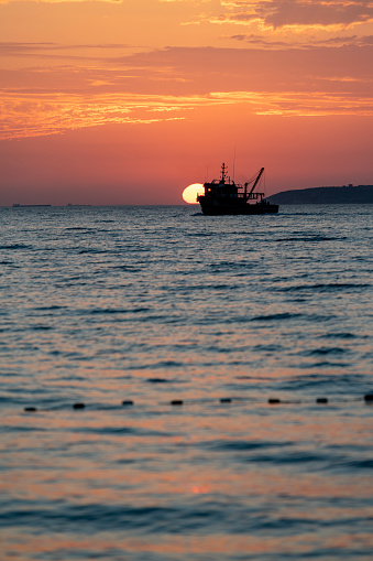 Beautiful golden sunset over Aegean Sea with fishing boat.