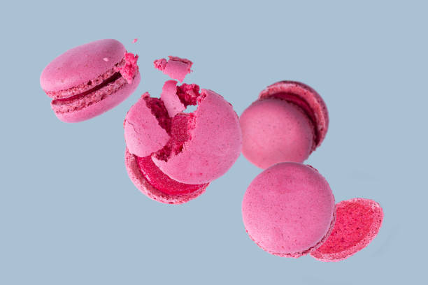 istock French dessert - pink macarons on purple background, flying food 2055573521