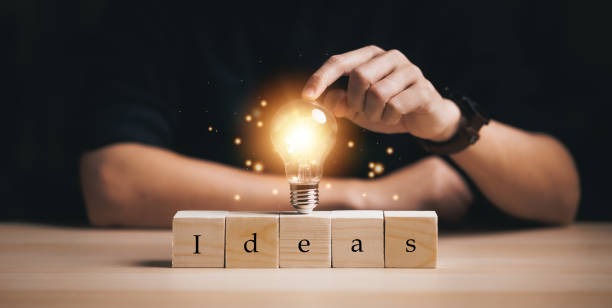 istock hand touching on light bulb on wood block with Word Ideas, innovative technology in science and communication concept, new idea concept with innovation and inspiration. 2055574061