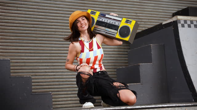 Portrait of smiling young person with boom box on ramp at skate park