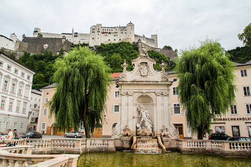 Salzburg, Austria - July 07, 2020 - Beautiful chapter fountain and the Hohensalzburg fortress in Salzburg, Austria