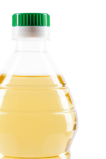 Plastic bottle of vegetable cooking oil close up on white background