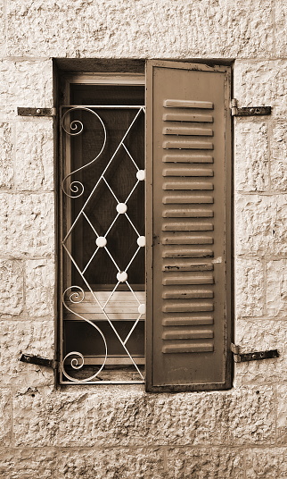 Sepia-Toned Nostalgia: Old Window with Iron Bars and Wooden Shutter. The timeless aesthetic of vintage architecture captured in monochrome