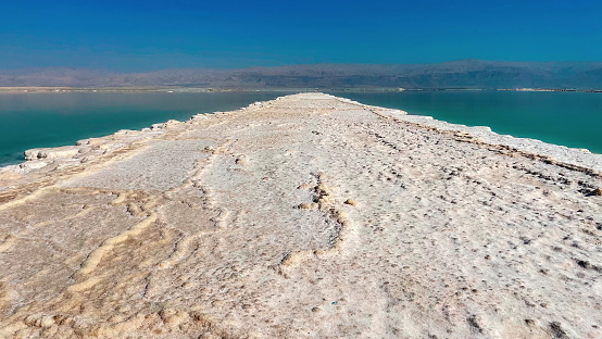 Natural Marvel: Salt Pathway in the Dead Sea. The Striking Contrast of Saline Deposits Against Crystal Blue Waters